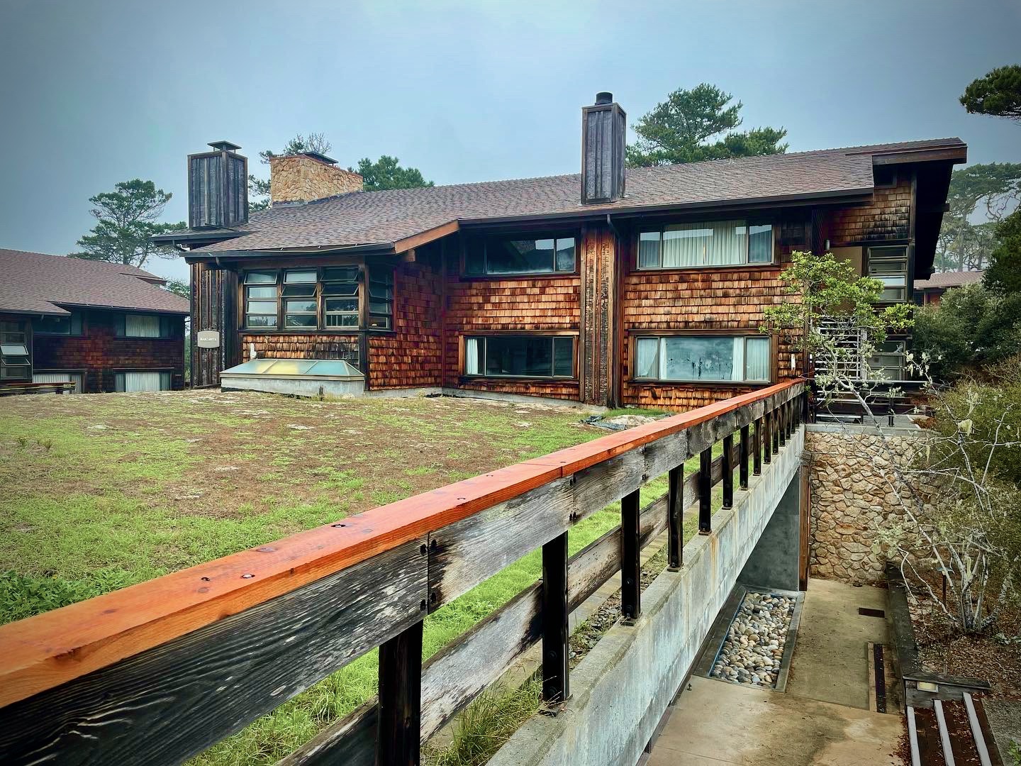 A grassy walkway leading to a red shingled building on the Asilomar Conference Grounds