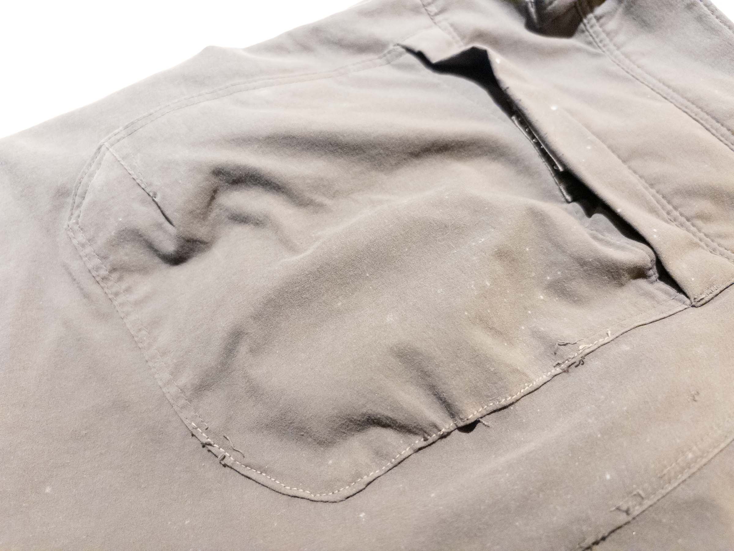 Close-up of worn gray hiking pants with a tear neatly sewn up
