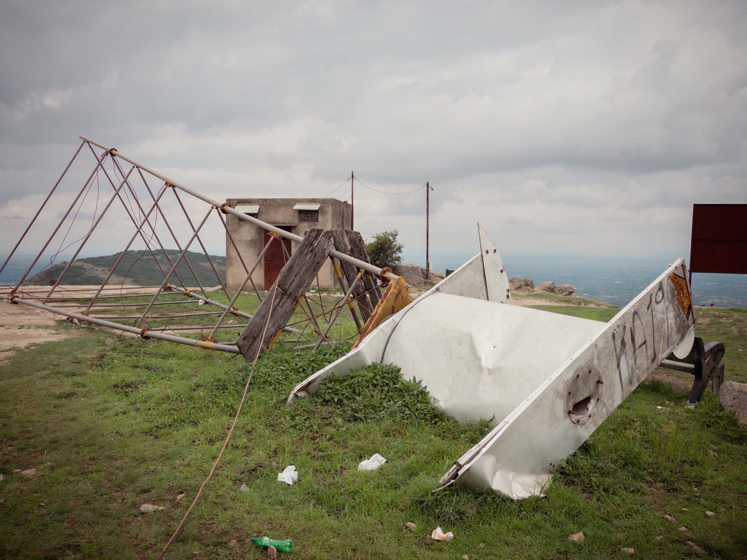 A collapsed lattice tower and a toppled white microwave dish on the hilltop