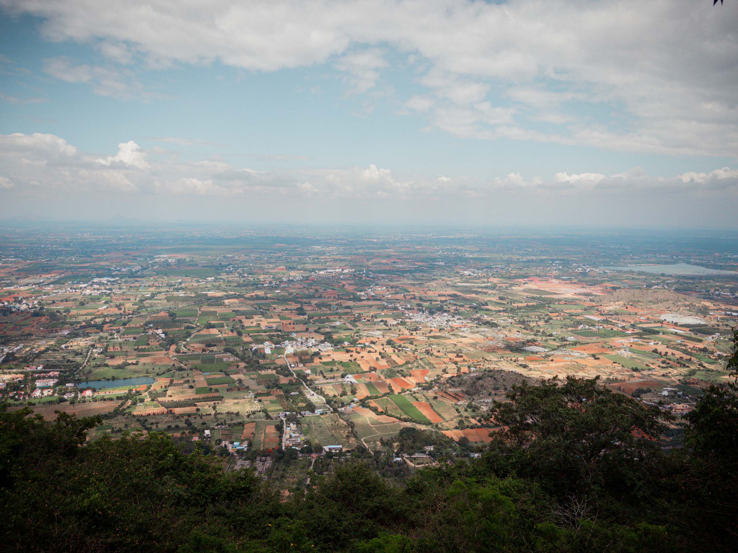 A sunny view of patchwork farmland on the plains far below the summit