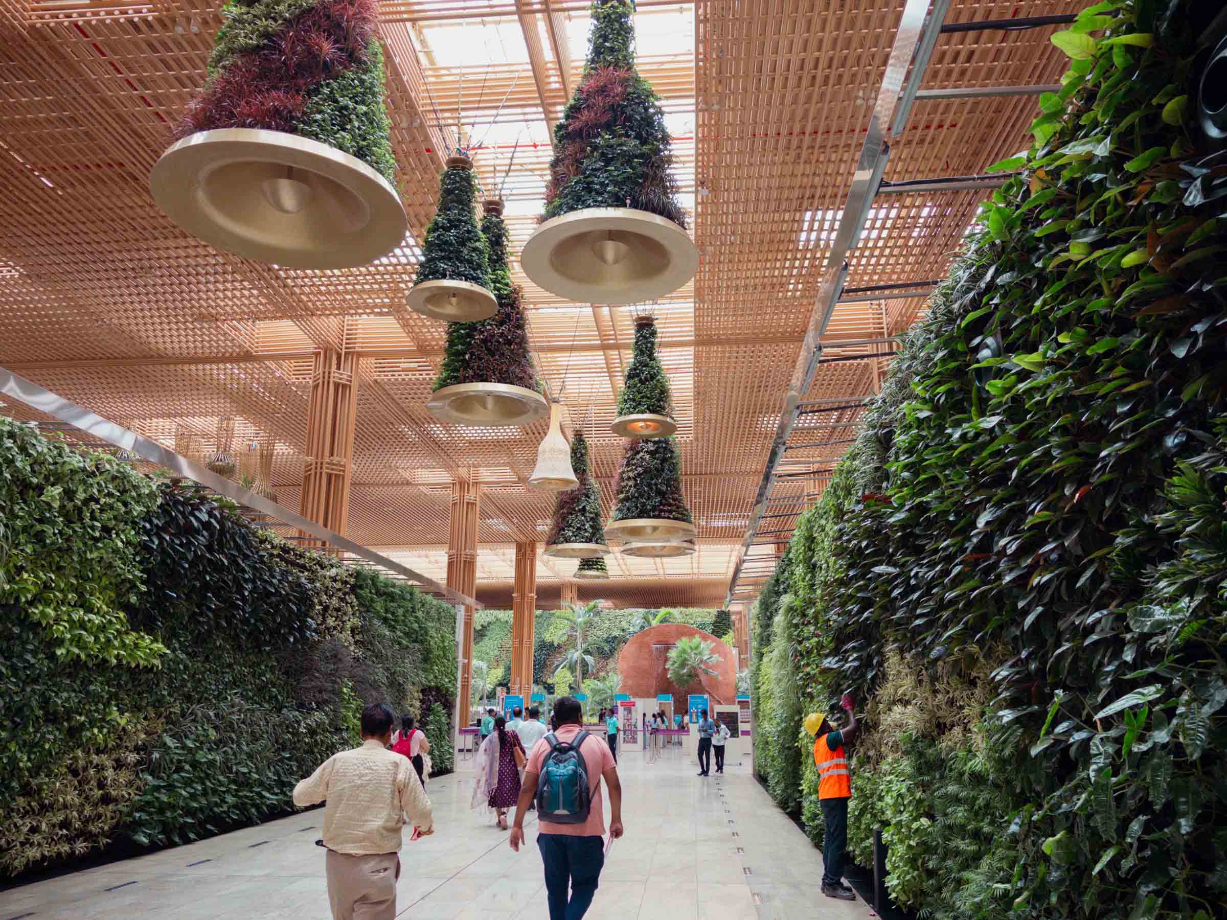 An airport concourse hung with cone-shaped planters, its walls lined with living plants