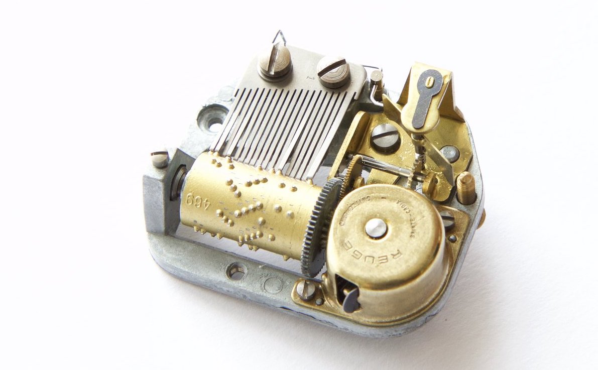 Photo of a brass clockwork mechanism with a studded cylinder that rotates against a comb of brass teeth of different lengths
