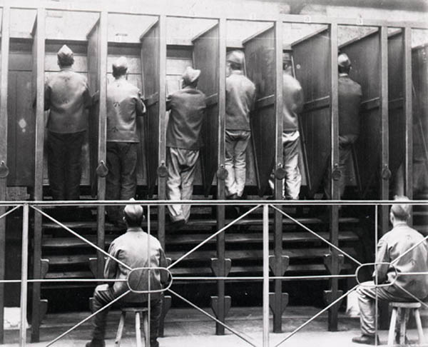 Photograph of prisoners at Pentonville Prison standing in a row on a treadmill, each in a separate stall