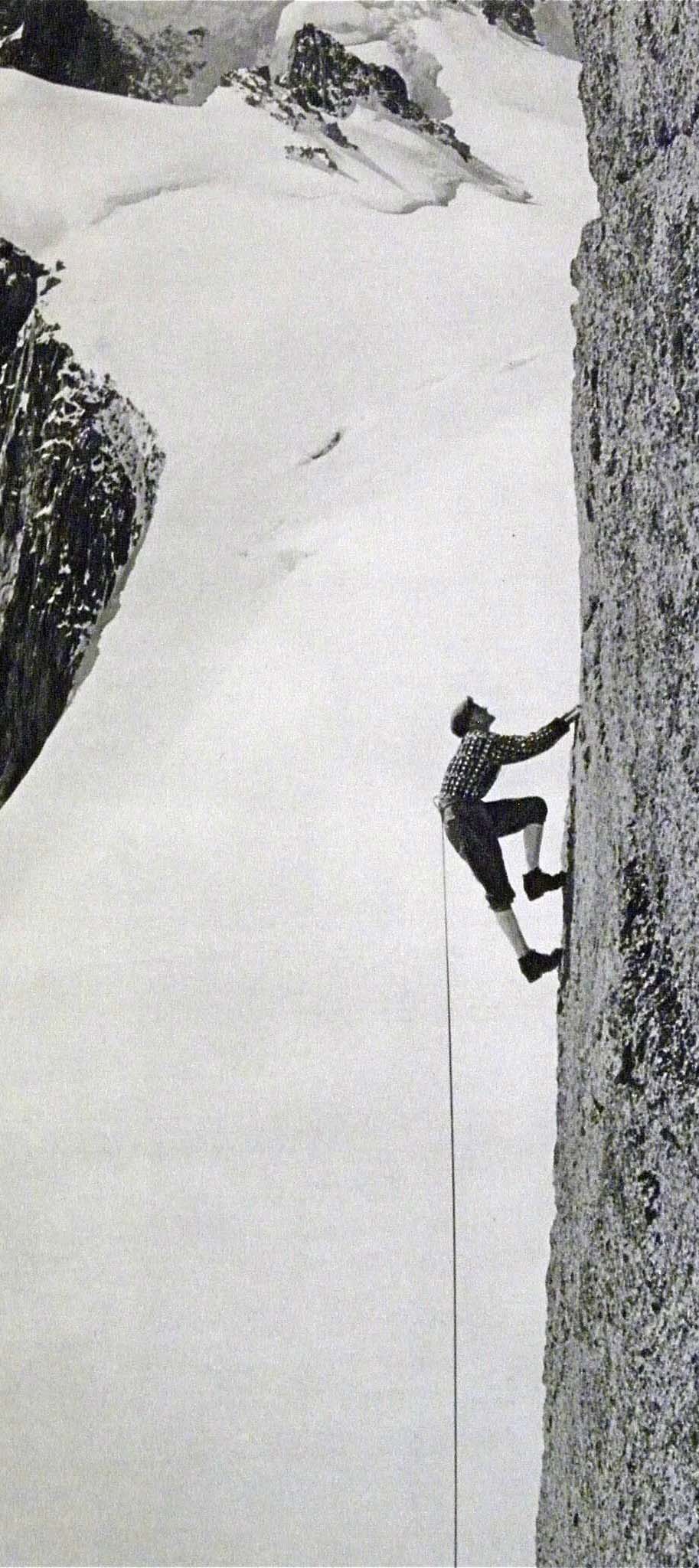 Black and white photo of 1940s-era climber ascending a vertical rock wall