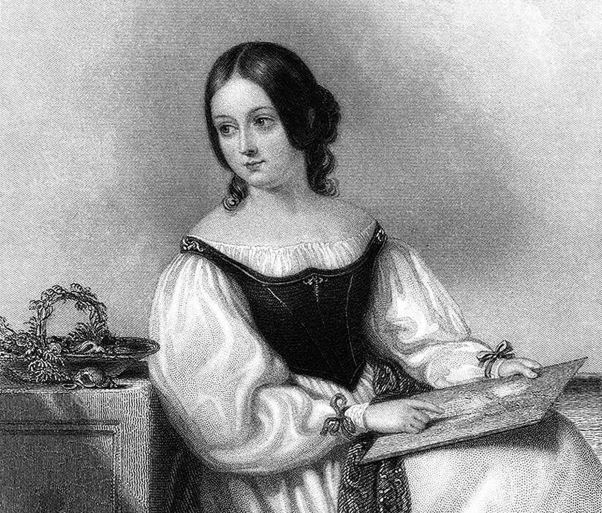 A seated woman is holding a drawing, probably representing somebody’s portrait. She’s pointing a finger at a detail in the picture while turning her head to the left, as though talking to someone outside the frame of the image.