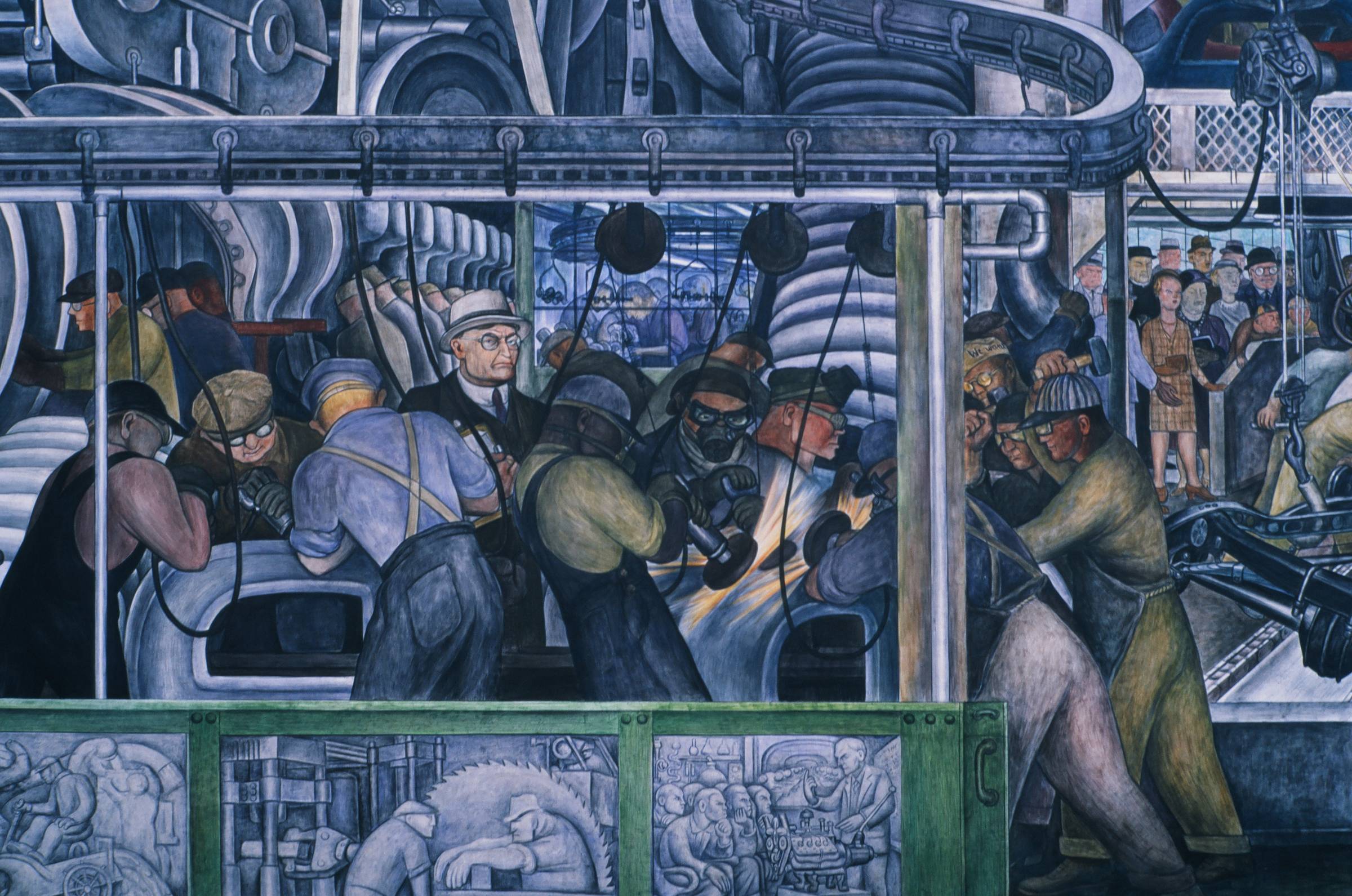 Detail from a Diego Rivera mural showing factory workers laboring among heavy machinery, observed by a man in a suit and glasses.
